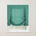 Teal linen balloon shade with decorative top loops and buttons, elegantly gathered at the bottom, covering a white-framed window overlooking a bright green garden