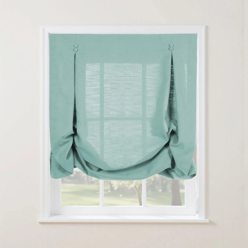 Light teal linen tie-up Roman shade featuring decorative buttons at the top and a gathered bottom revealing a verdant outdoor landscape through the window