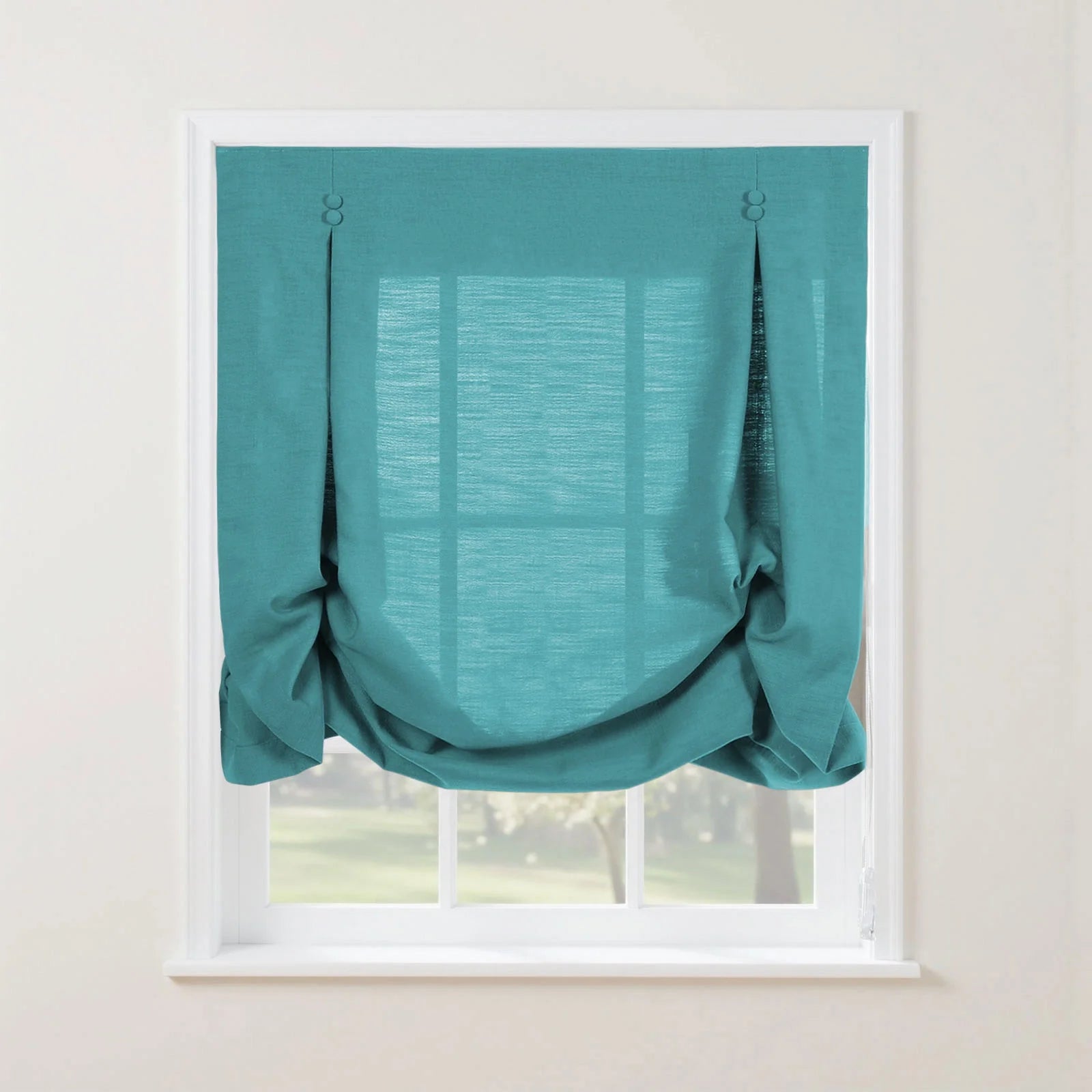 A vibrant teal textured balloon Roman shade covers a white window, featuring two decorative top buttons and soft gathers, with a blurred green garden visible beyond