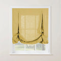 A golden yellow linen-textured tie-up Roman shade featuring decorative loops partially covers a white-framed window overlooking blurred green trees