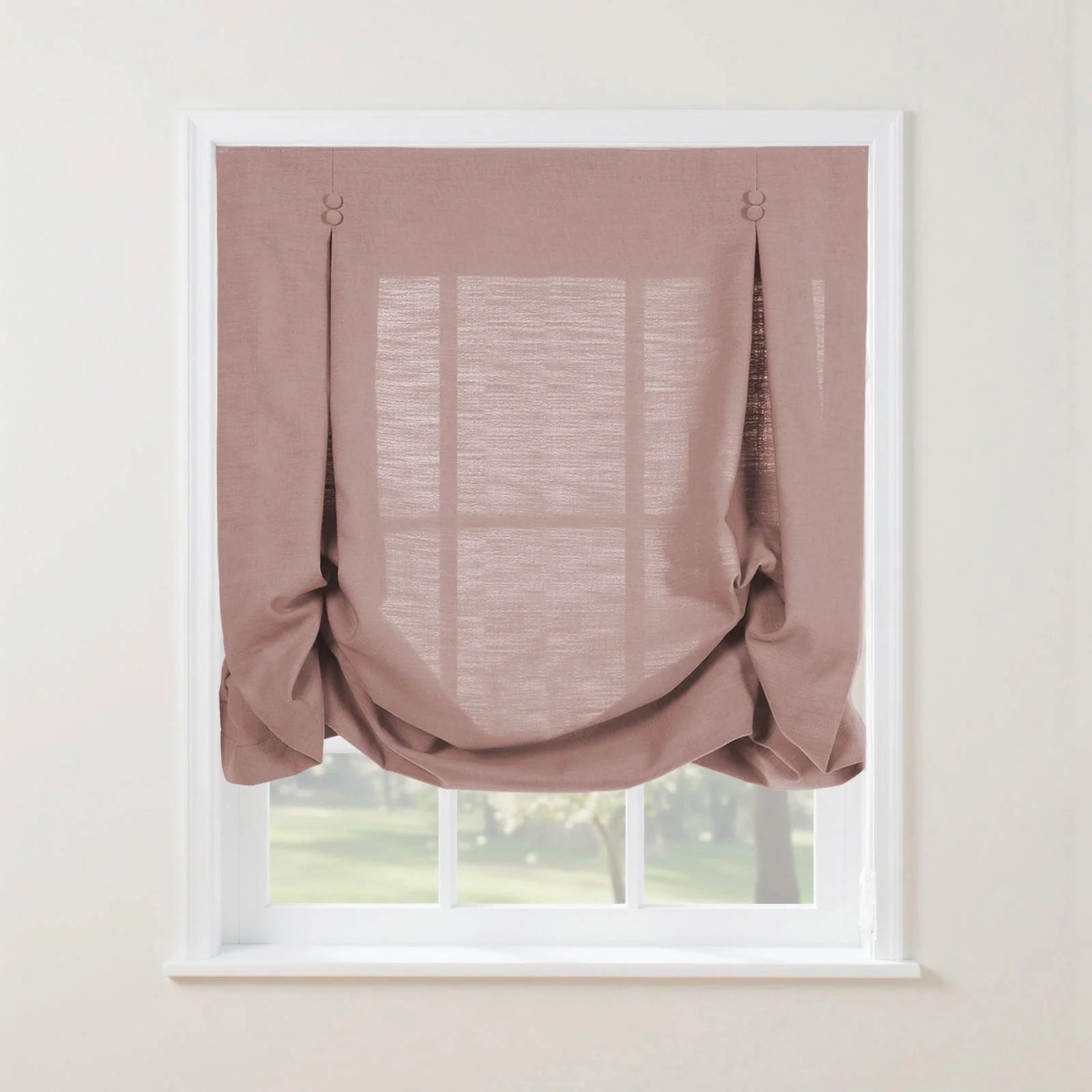 Dusty rose linen-look Roman window blind with decorative fabric button loops creating soft relaxed folds in a white frame overlooking a vibrant green garden