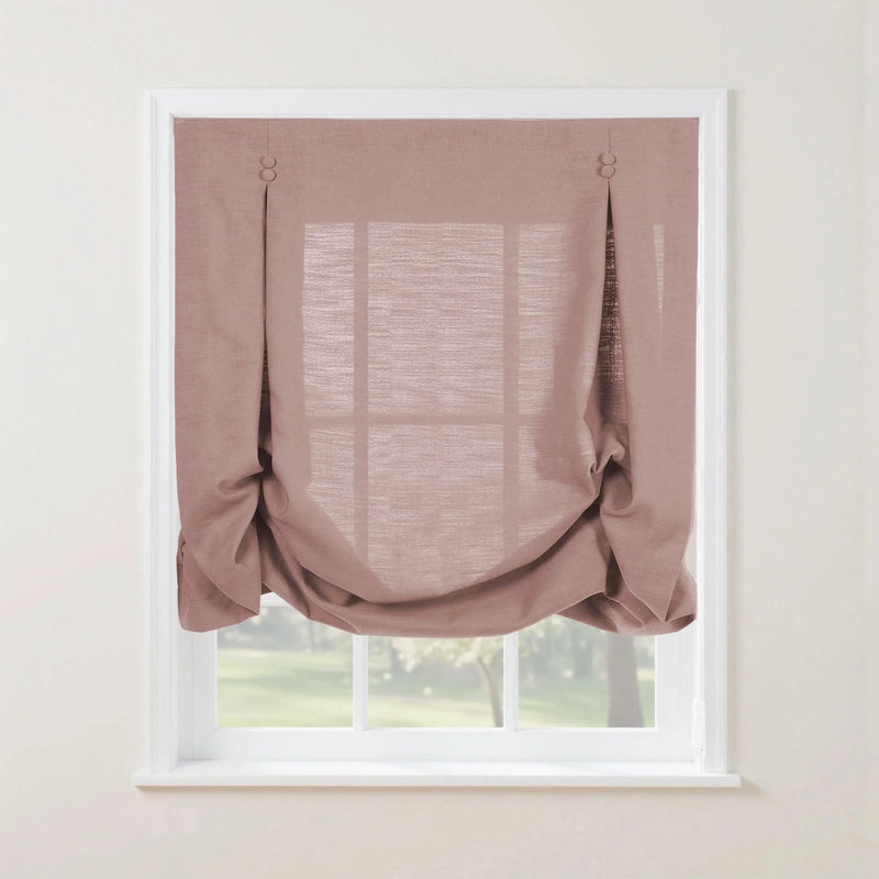 Dusty rose linen-look Roman window blind with decorative fabric button loops creating soft relaxed folds in a white frame overlooking a vibrant green garden