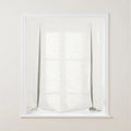 A white textured linen-look Roman window blind with exposed dark cords, light ring fasteners, and a soft bottom drape allowing the window grid to subtly show through