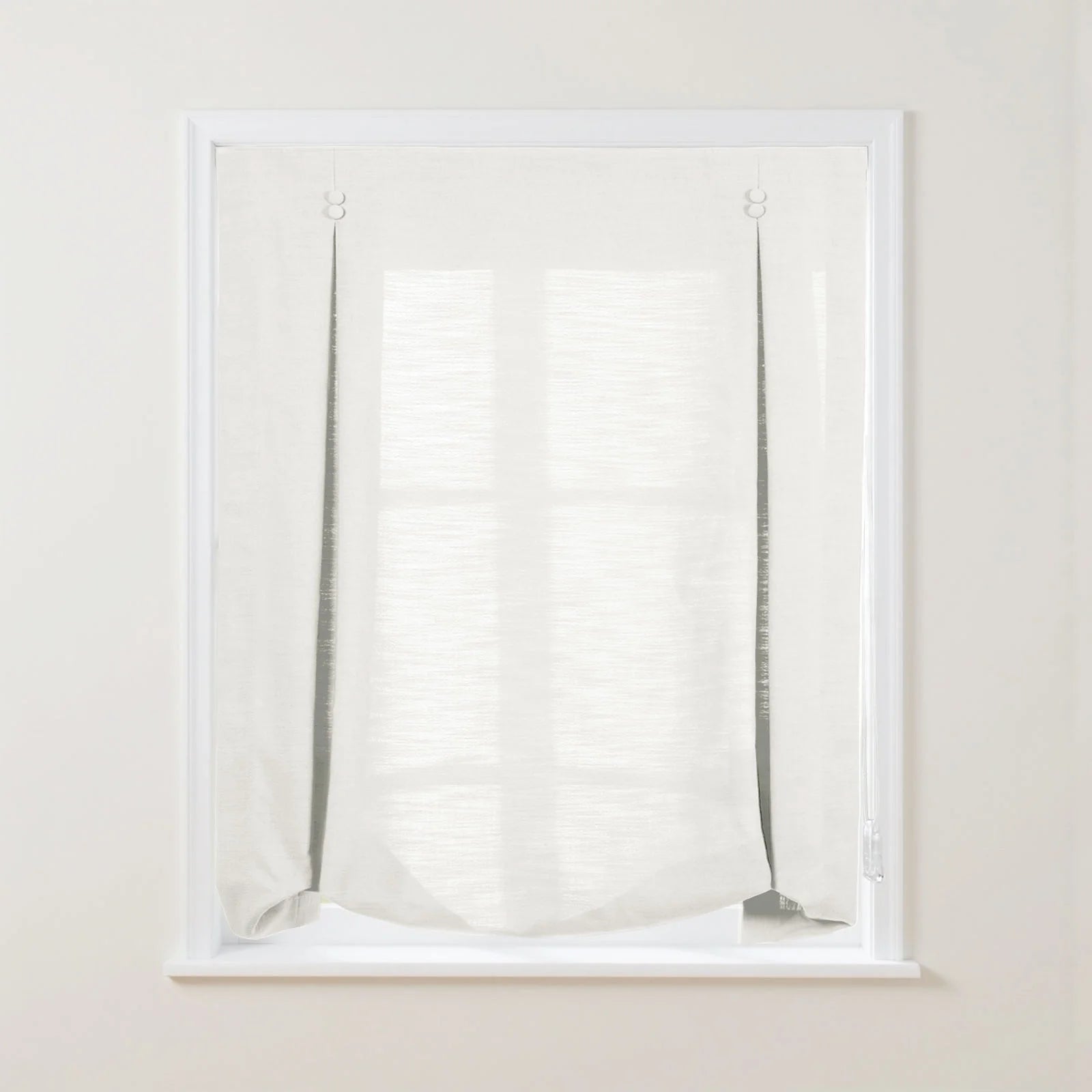 A white textured linen-look Roman window blind with exposed dark cords, light ring fasteners, and a soft bottom drape allowing the window grid to subtly show through