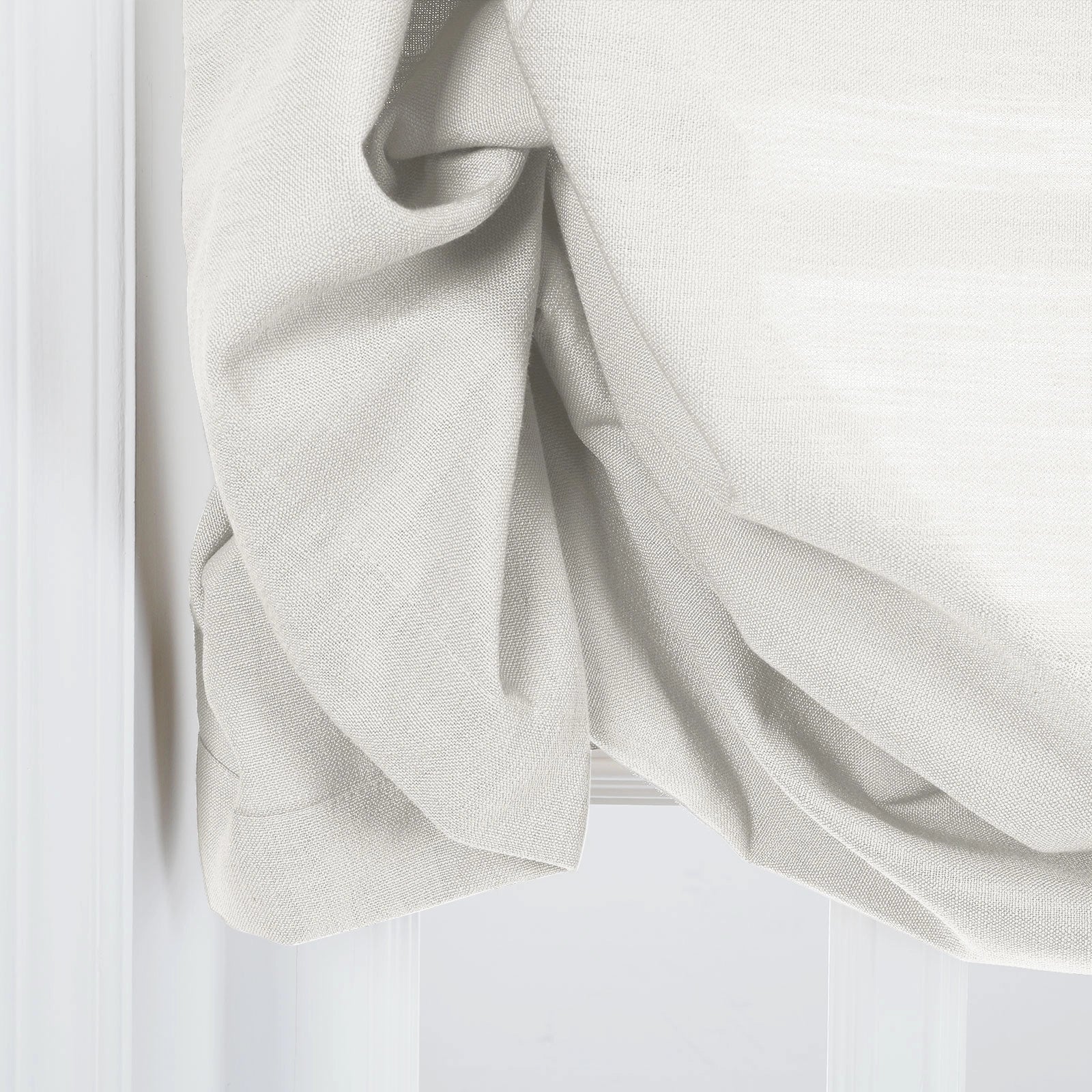 Close-up of an off-white textured linen curtain featuring soft drapes and subtle folds next to a crisp white window trim