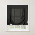 Dark charcoal linen-look tie-up curtain with decorative buttoned loops at the top and a softly gathered bottom on a white window frame overlooking a lush green outdoor view