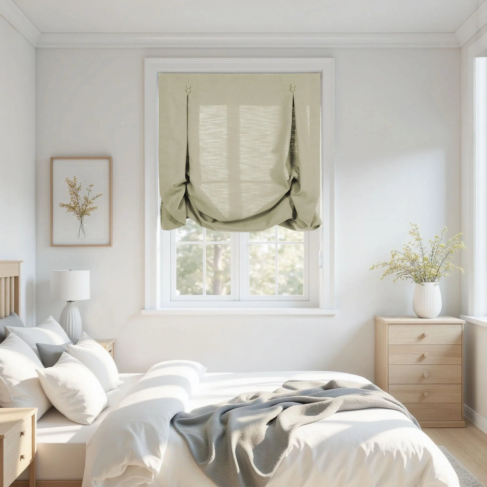 A bright minimalist bedroom features a large window with a sage green balloon shade, a framed dried floral artwork, and a white ribbed vase holding yellow sprigs