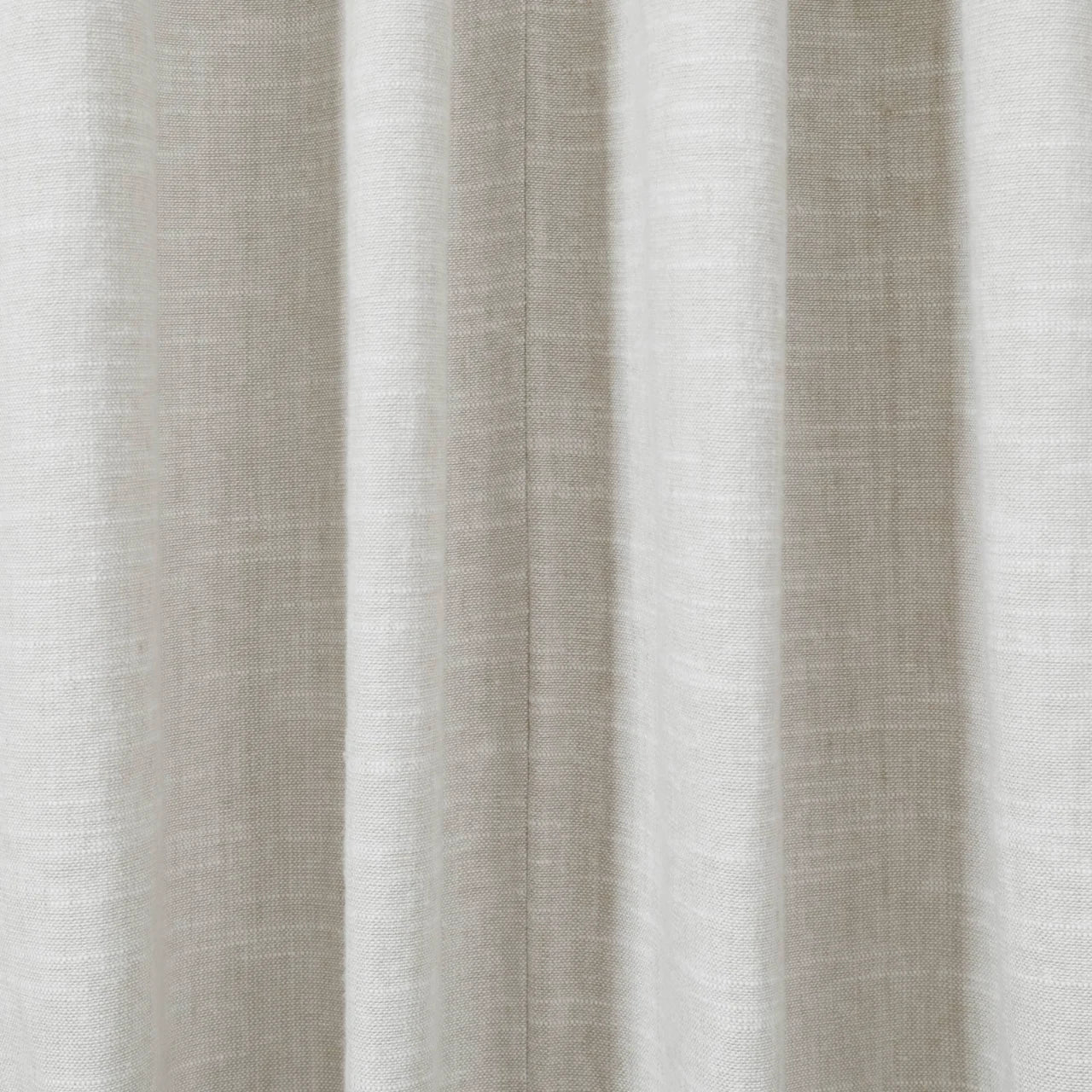 Photograph of light beige textured fabric draped in soft vertical pleats featuring a subtle central seam