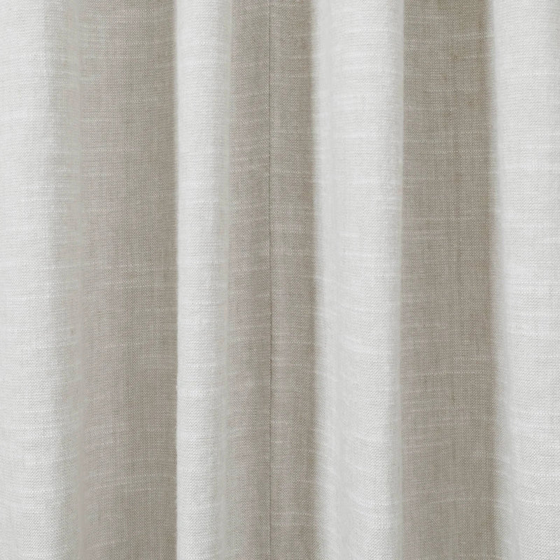 Photograph of light beige textured fabric draped in soft vertical pleats featuring a subtle central seam