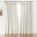 Off-white linen-look tie-top curtains featuring decorative bows on a black rod in a bright room with a warm wooden floor and a glimpse of a small framed landscape painting