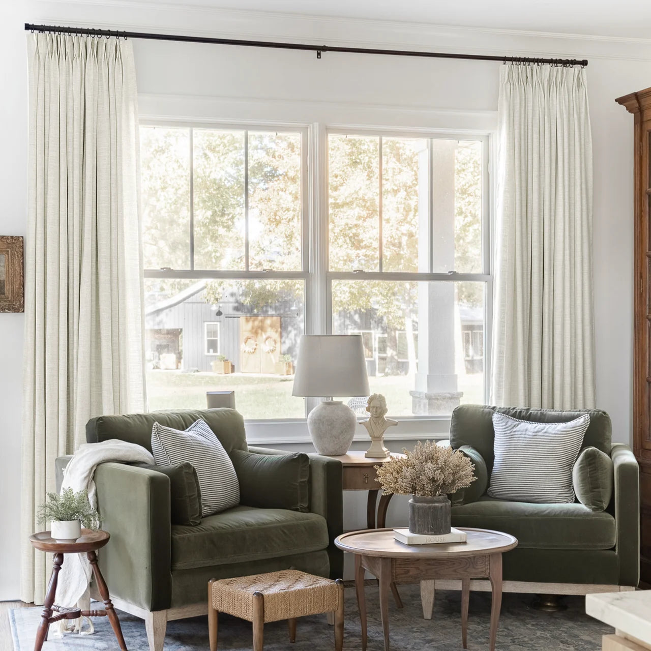 Ivory White Liz Linen Pleated Curtains beside a green sofa, table lamps and nested coffee tables