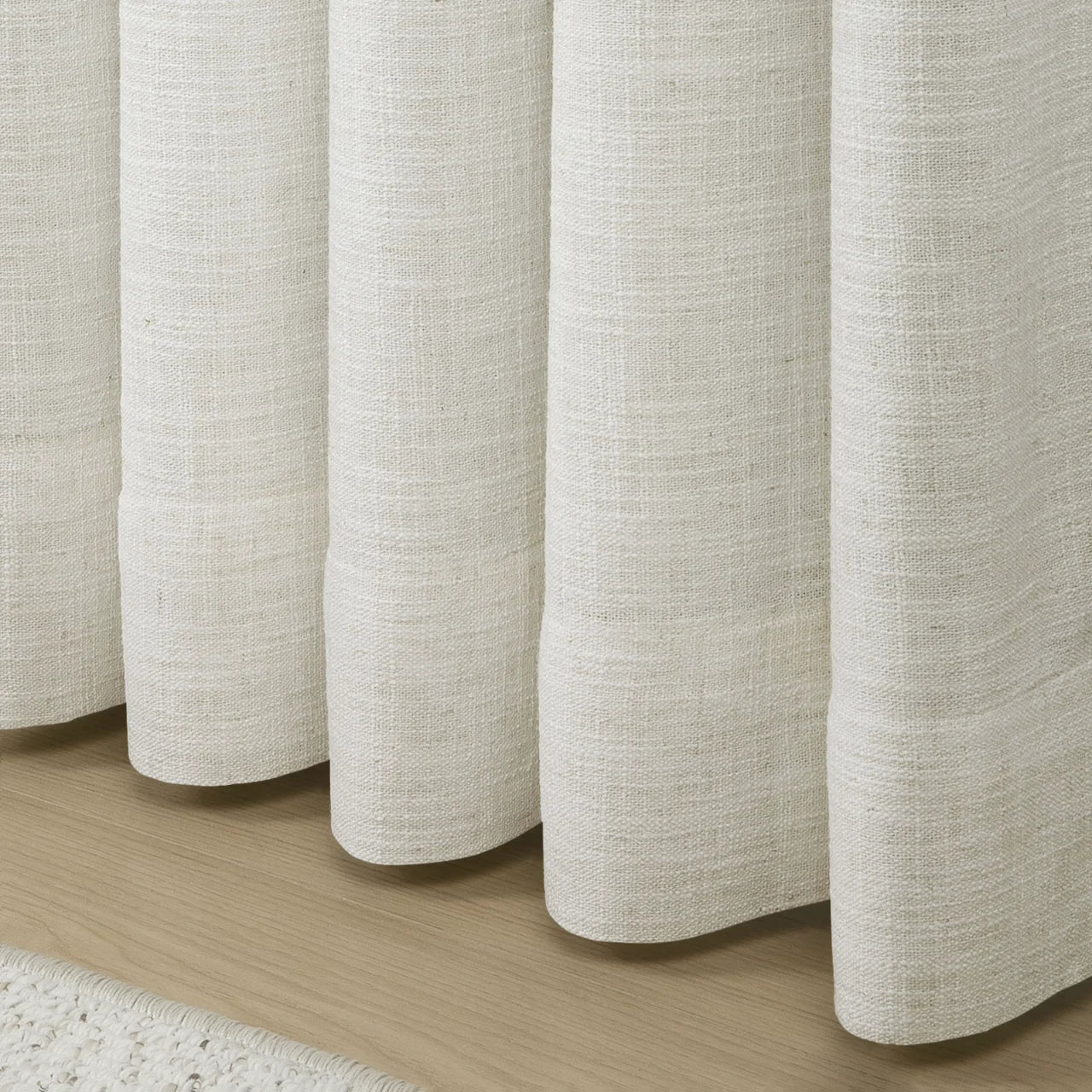 Ivory White Liz Linen Pleated Curtains rounded curtain hems above a pale wood floor