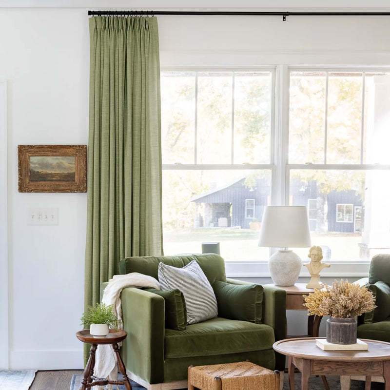 Jade Green Olive Liz linen curtains shown closer beside a sunlit window with smooth vertical folds