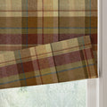 Wool blend Roman blind in a traditional earthy plaid pattern featuring shades of brown, olive, and cream with subtle maroon and blue accent lines, partially lowered at a window revealing a soft fabric fold