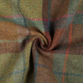 Woolen tweed fabric displaying a rustic plaid pattern featuring squares of moss green, russet, and gold with thin accent lines of fuchsia, sky blue, and deeper brown in a visible twill weave, gently swirled to show its rich texture