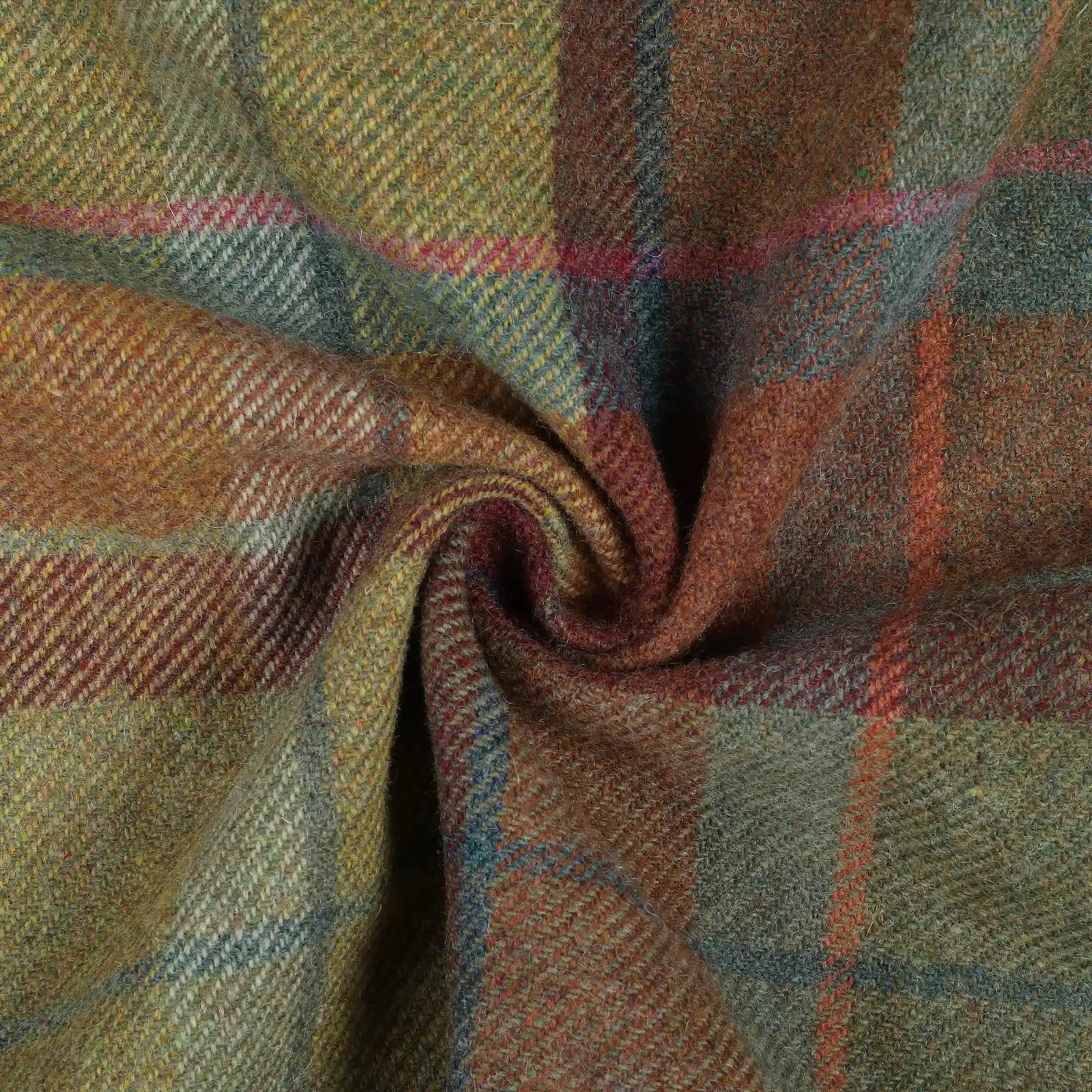 Woolen tweed fabric displaying a rustic plaid pattern featuring squares of moss green, russet, and gold with thin accent lines of fuchsia, sky blue, and deeper brown in a visible twill weave, gently swirled to show its rich texture