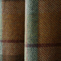 Close-up of a rustic woven plaid fabric featuring earthy browns and yellows accented by wide blue-green stripes and subtle maroon lines with a coarse, fuzzy texture