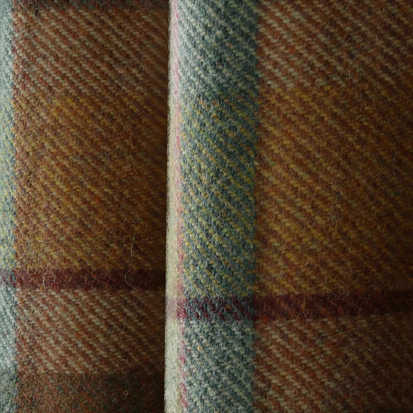 Close-up of a rustic woven plaid fabric featuring earthy browns and yellows accented by wide blue-green stripes and subtle maroon lines with a coarse, fuzzy texture