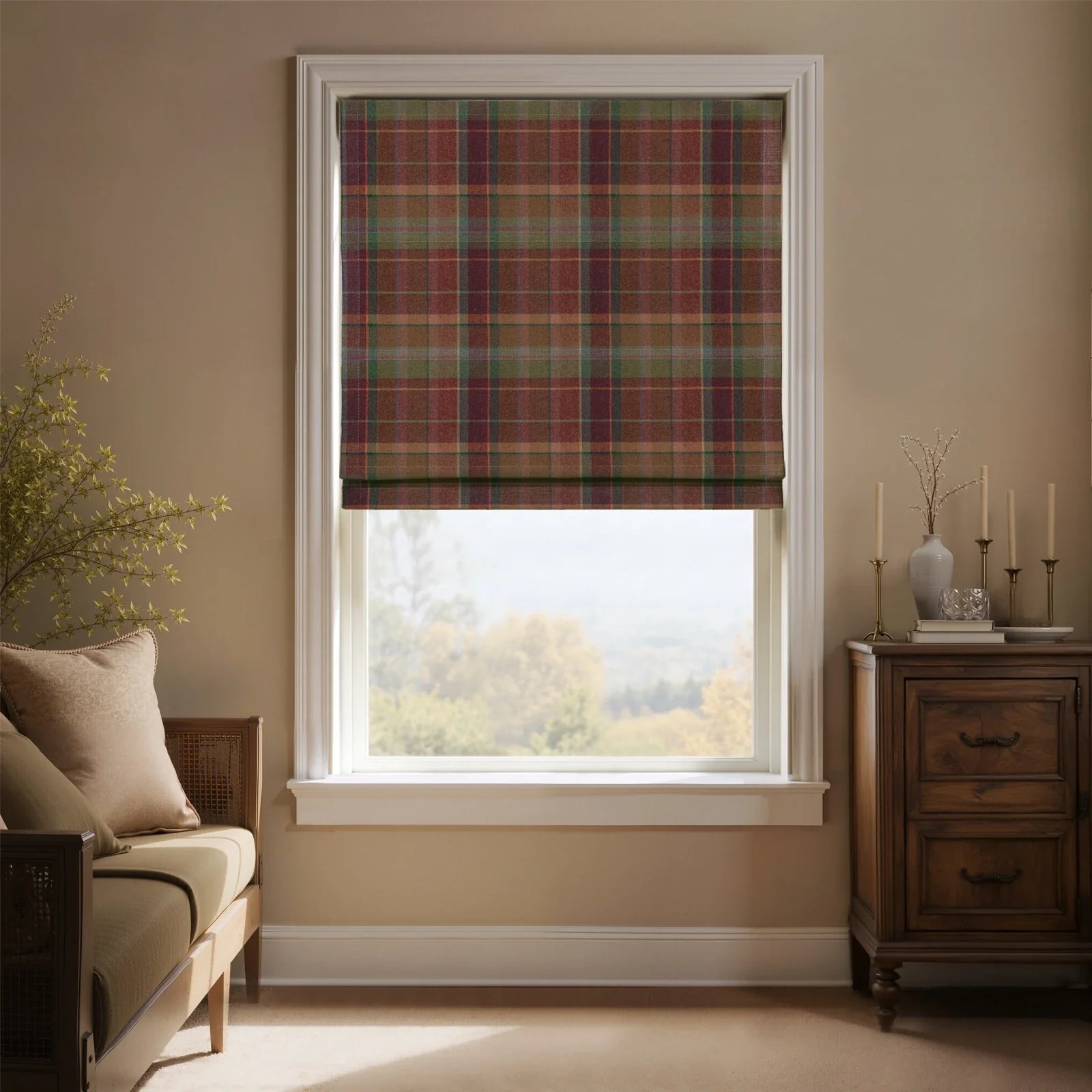 Interior shot of a cozy room featuring a window with a red, green, and brown tartan plaid Roman blind overlooking a distant autumn landscape, a wood daybed with neutral cushions, and a dark antique cabinet decorated with brass candlesticks