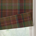 A Roman blind featuring a rich earthy tartan pattern with dominant brown, maroon, and olive green hues accentuated by fine blue and purple lines shown with a soft fold against a blurred window view