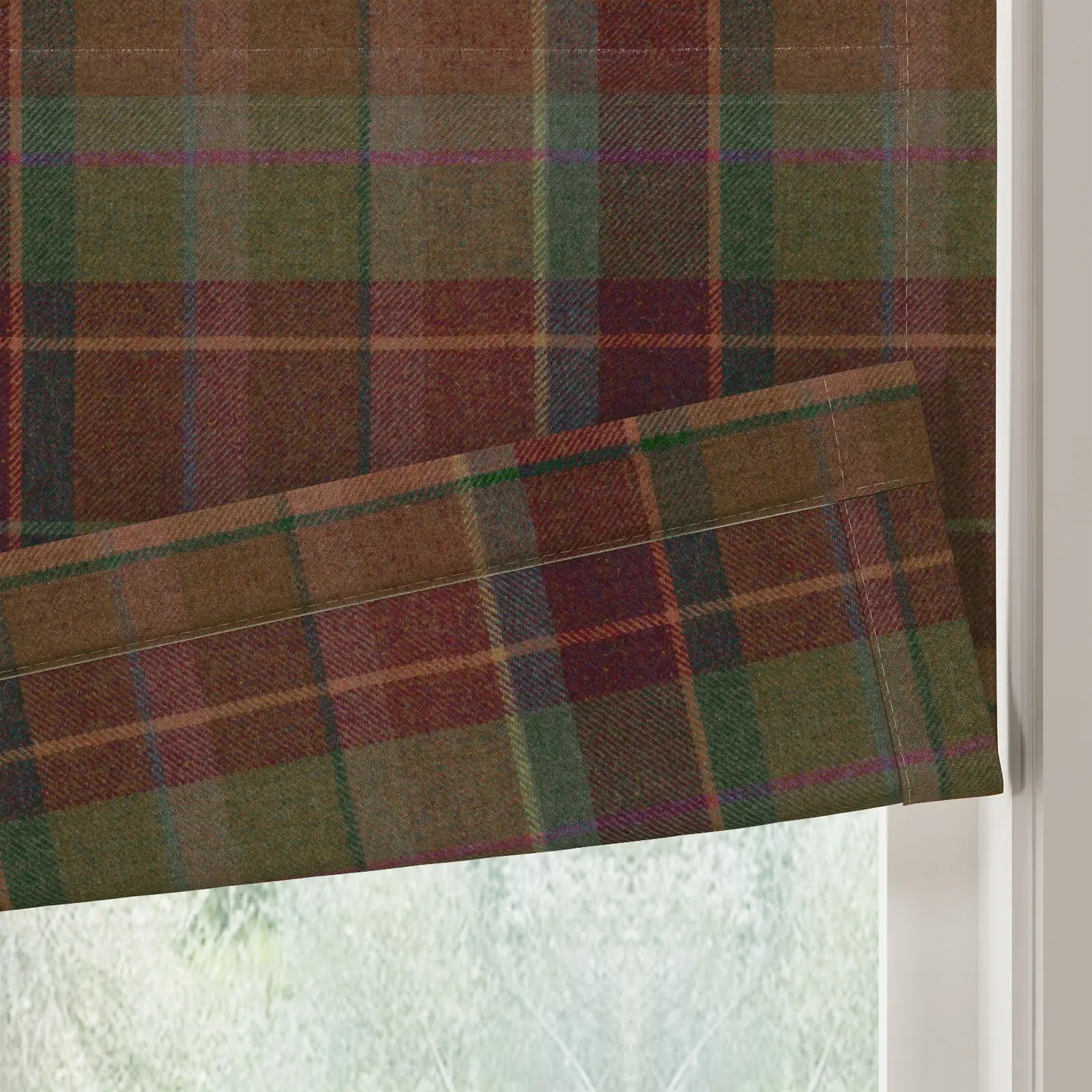 A Roman blind featuring a rich earthy tartan pattern with dominant brown, maroon, and olive green hues accentuated by fine blue and purple lines shown with a soft fold against a blurred window view