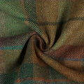 Draped tweed fabric with a classic plaid pattern in earthy greens, warm browns, and deep rust, accented by thin blue and red lines