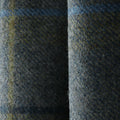 A close-up of folded dark grey-blue wool fabric with visible textures, featuring subtle olive green and light blue threads woven throughout
