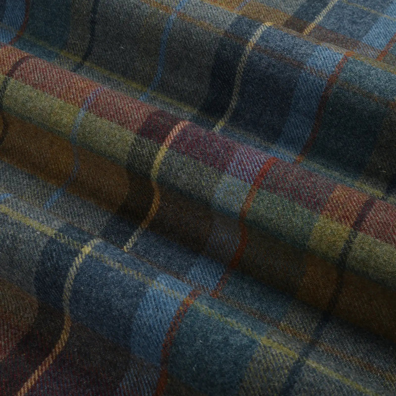 Textile featuring a woven wool plaid fabric in rich shades of dark blue, deep maroon, olive green, and brown, highlighted by thin golden yellow and rust orange stripes, draped in soft folds