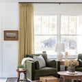 Khaki Liz linen curtains shown closer beside a sunlit window with smooth vertical folds