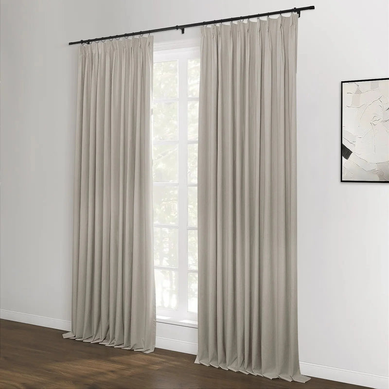 Beige pleated curtains on a black rod flank a large white window in a contemporary room featuring a dark wood floor and a minimalist black and white abstract artwork