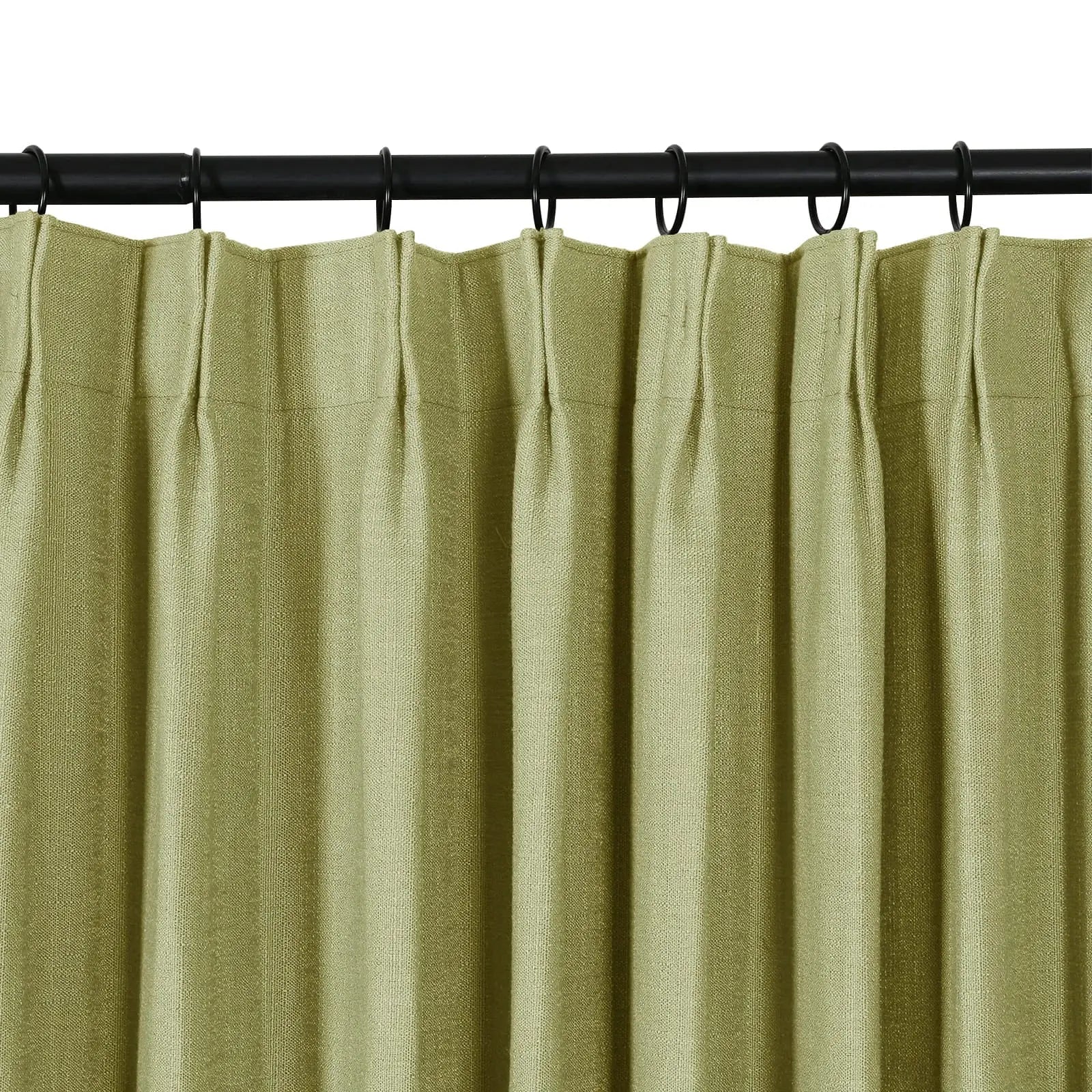 A close-up of a sage green textured curtain with pinch pleats hanging from a black rod with rings