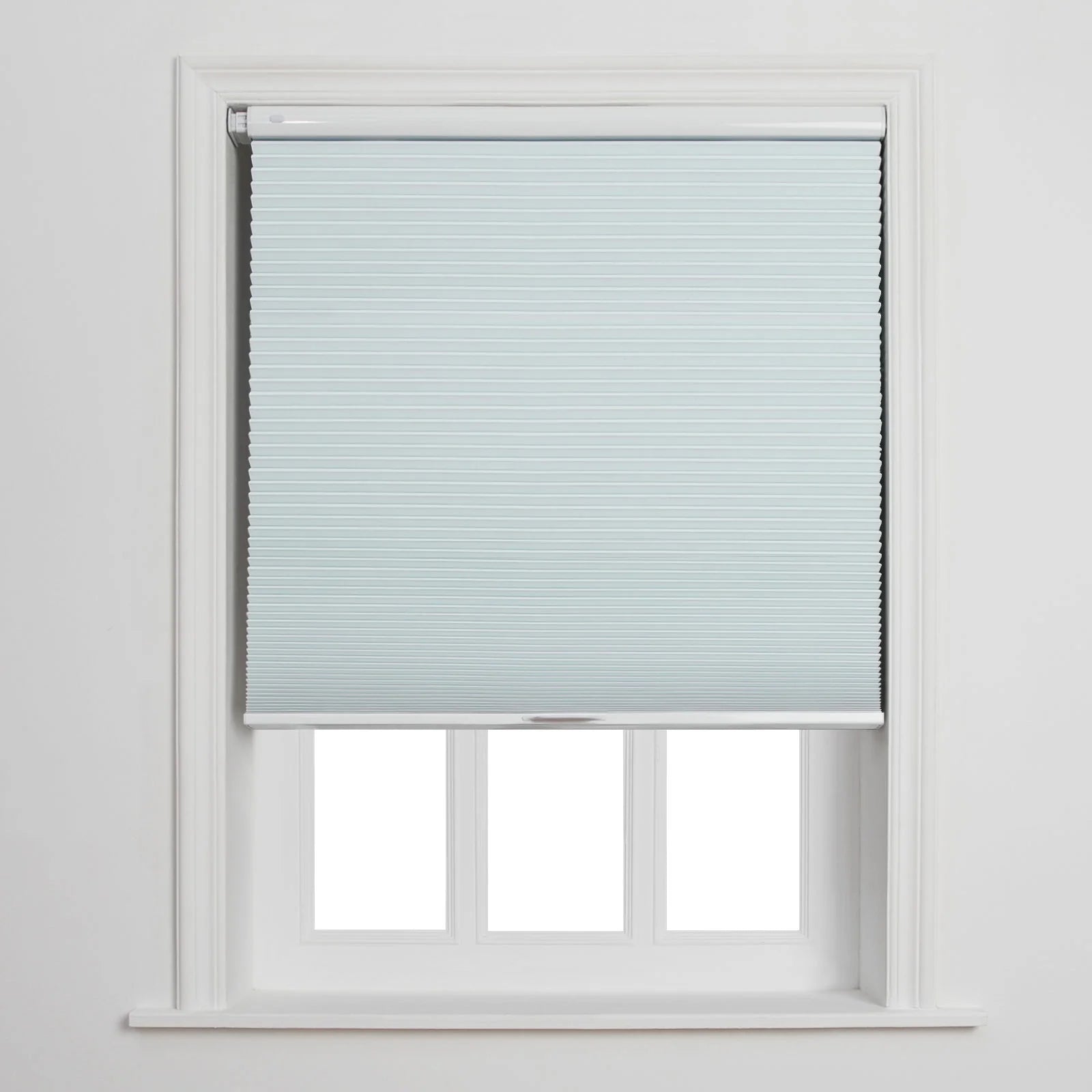 Photograph of a light blue cellular Blind partially covering a white-framed window with three visible lower panes against a plain white wall