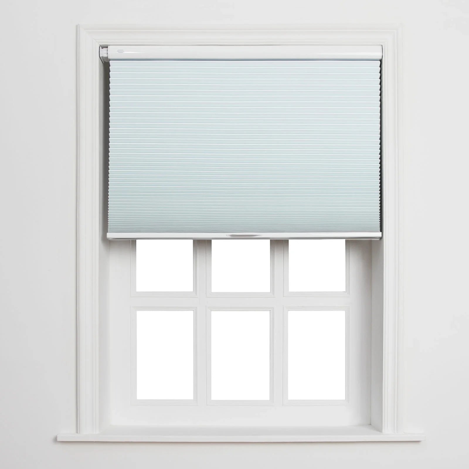 A light blue cellular pleated Blind partially unrolled over a white six-pane window with clean white trim