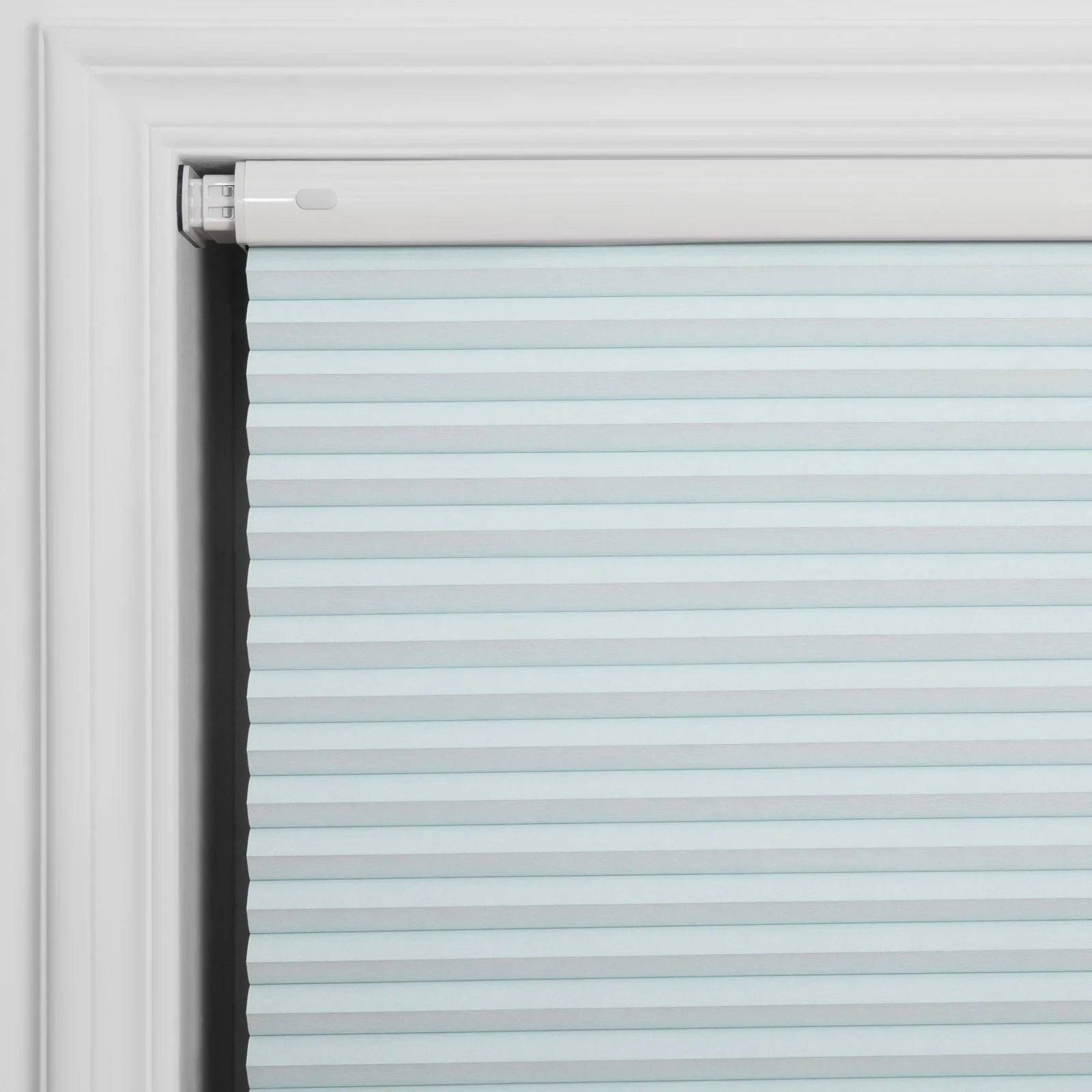 Light blue cellular window Blind installed within a white window frame featuring horizontal pleats and a white top-down mechanism with a small oval button