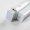Product photo of a white motorized window Blind mechanism featuring light blue striped fabric, a grey control button, and a transparent mounting bracket