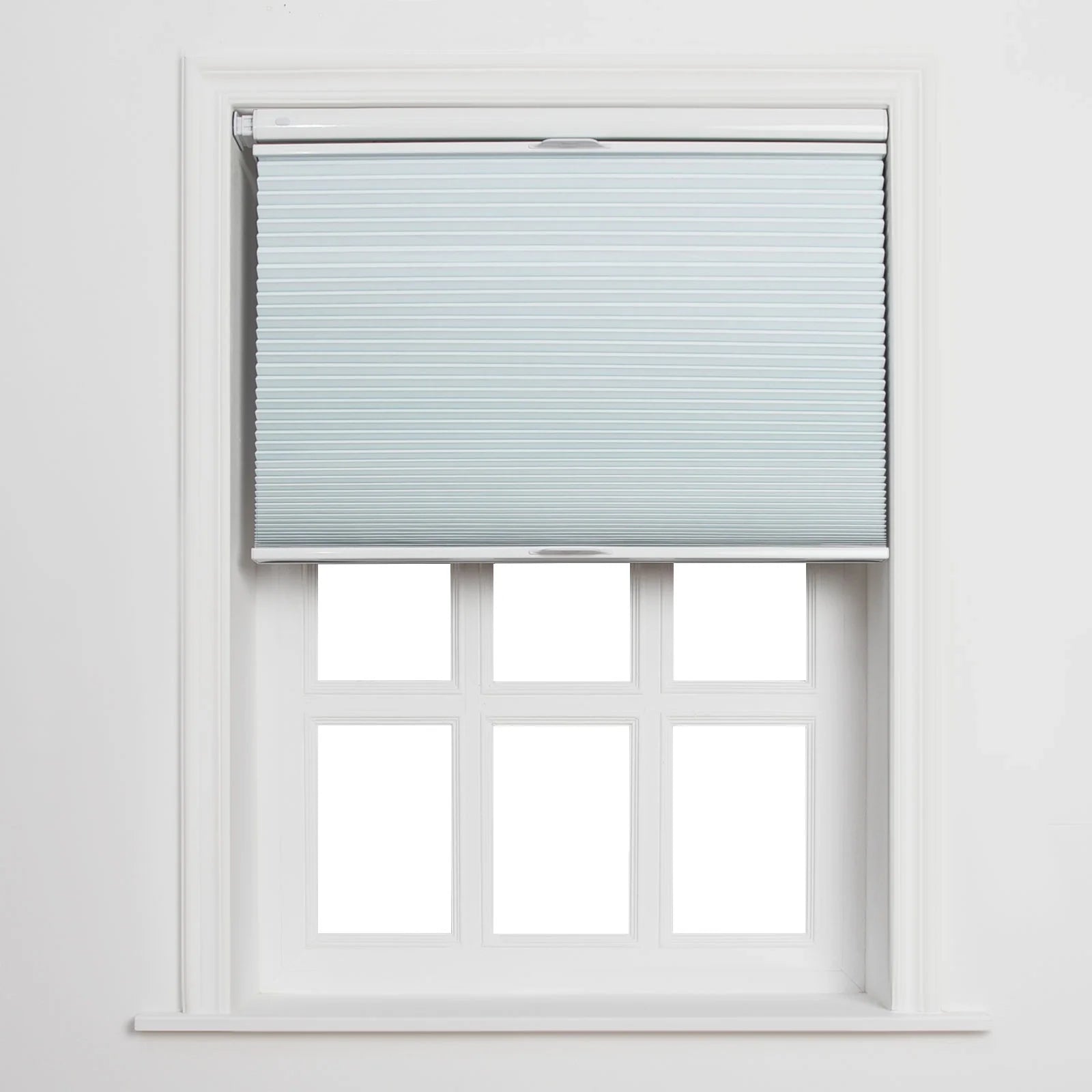 Light blue pleated cellular Blind covering the top portion of a clean white multi-pane window featuring six clear sections and a prominent sill, set against a crisp white interior wall