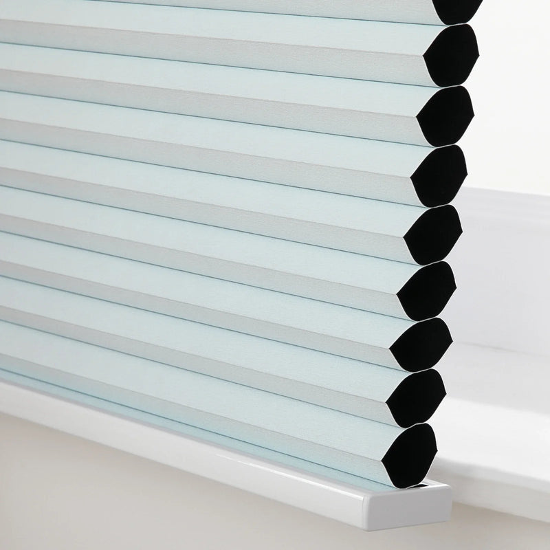 Close-up of light blue cellular honeycomb Blinds installed in a window showing black cells and a white bottom rail