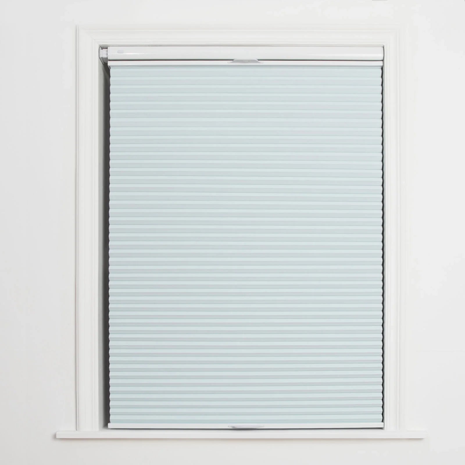 A window displaying a light blue cellular Blind with distinct horizontal pleats, framed by crisp white trim and featuring a discreet bottom rail handle