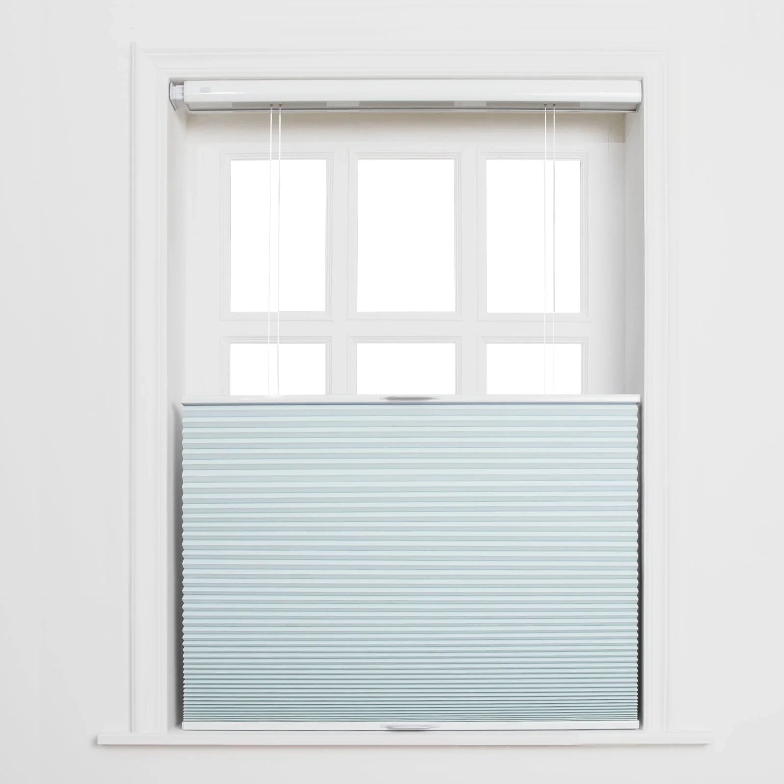 Photograph of a white framed window with a light blue cellular top-down bottom-up Blind featuring subtle horizontal stripes and visible white pull cords, revealing the upper six panes