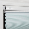 Photograph of a light blue cellular honeycomb window Blind installed in a white window frame, featuring a matching white headrail and neatly folded pleats