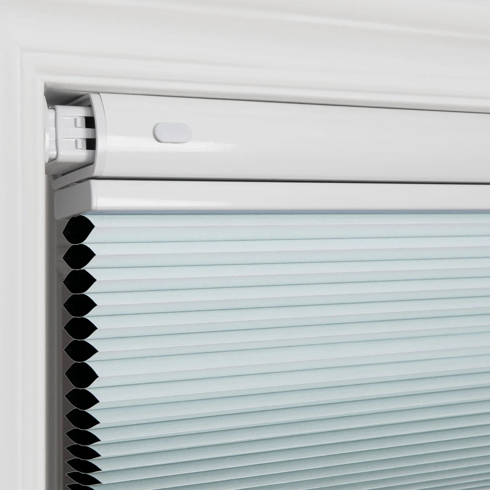 Photograph of a light blue cellular honeycomb window Blind installed in a white window frame, featuring a matching white headrail and neatly folded pleats