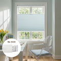 Photography of a modern home office featuring a bright window with light blue cellular Blinds, a white desk holding yellow tulips in a vase, and a transparent ghost chair with a blue gingham cushion, showcasing a "No Drill" installation detail