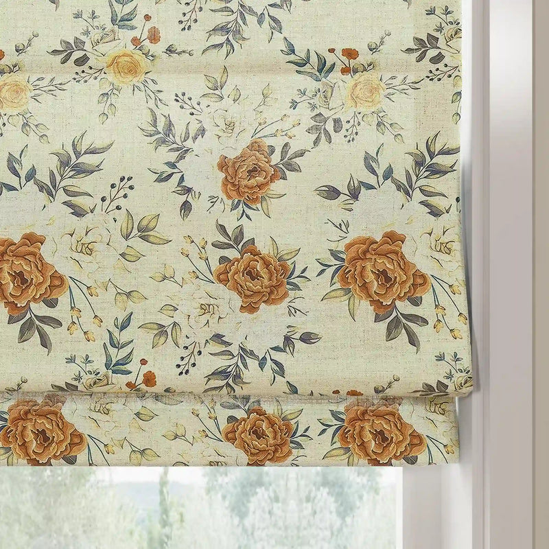Fabric photo of a patterned Roman blind featuring warm brown roses, delicate pale yellow blossoms, and elegant dark green leaves on a light cream textured fabric against a white window frame