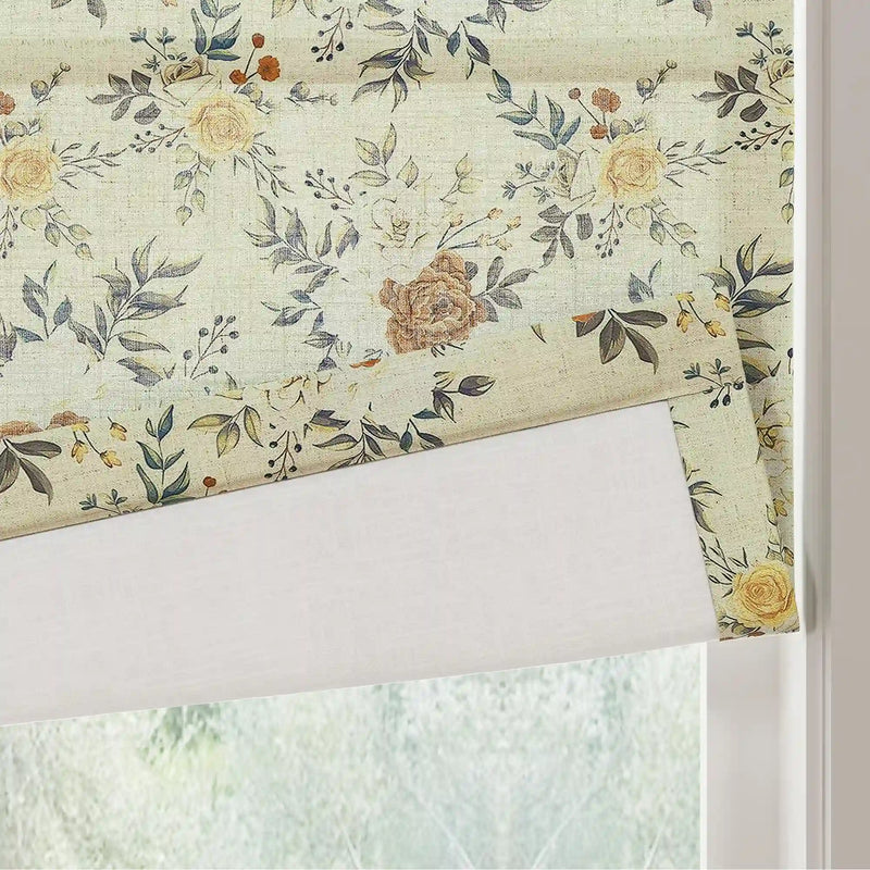 Textile fabric window blind with a vintage floral pattern featuring soft yellow roses muted blue-green leaves and rustic orange berries partially rolled up at an indoor window overlooking blurred green foliage