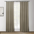 A pair of taupe grommet curtains on a black rod flanking a bright multi-paned window in a modern room with abstract wall art and a beige textured rug