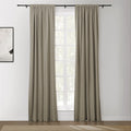 Beige rod pocket curtains frame a white grid window in a minimalist room with abstract wall art and a textured herringbone rug