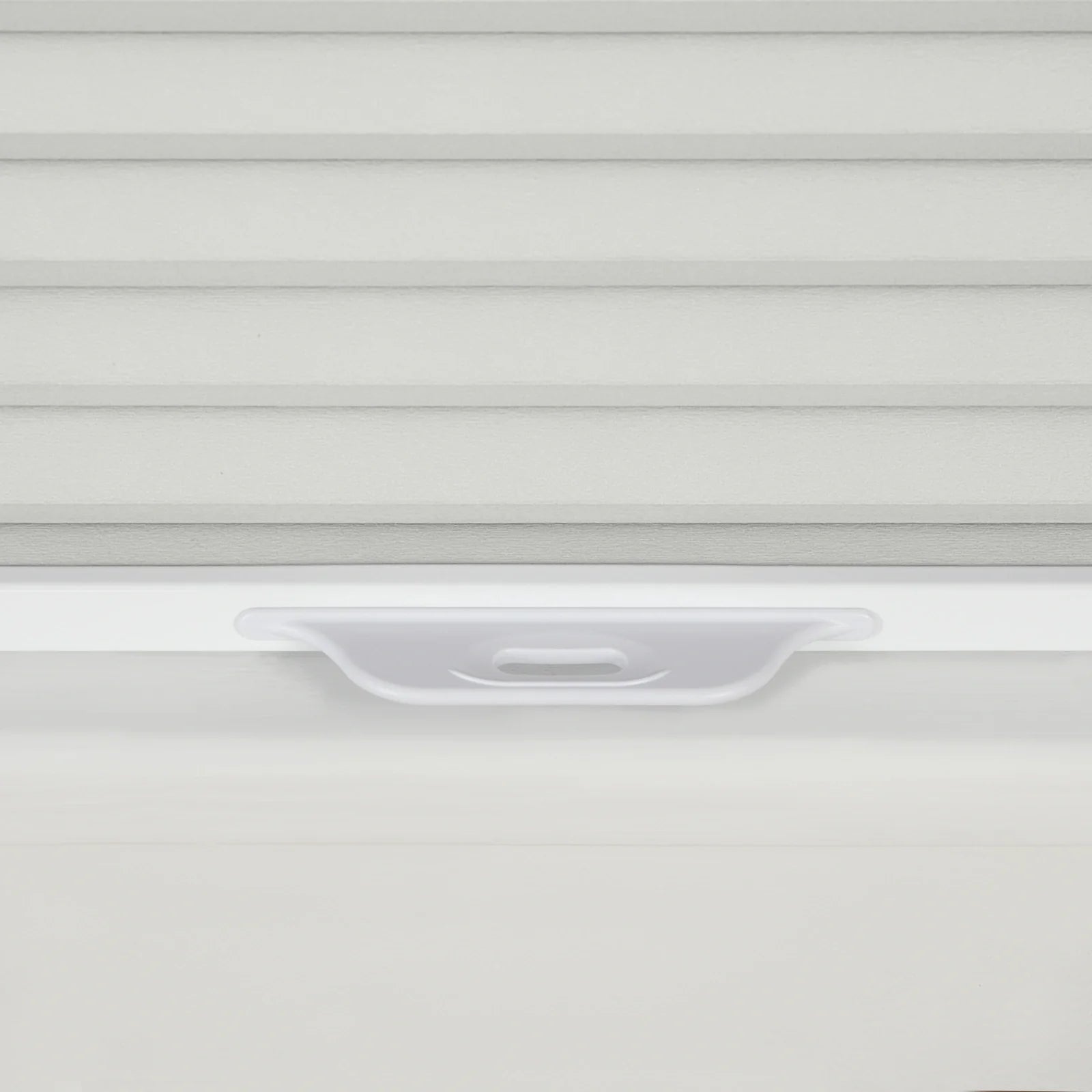 Close-up of textured light grey horizontal window Blinds with a translucent white plastic pull tab handle on a clean white windowsill