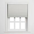 A clean interior image of a white window featuring a light gray pleated cellular Blind partially raised above six bright white panes, set against a minimalist white wall