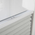 Photography of modern white pleated cellular Blinds on an interior window, featuring a crisp white top rail, two thin control cords, and textured gray-white fabric