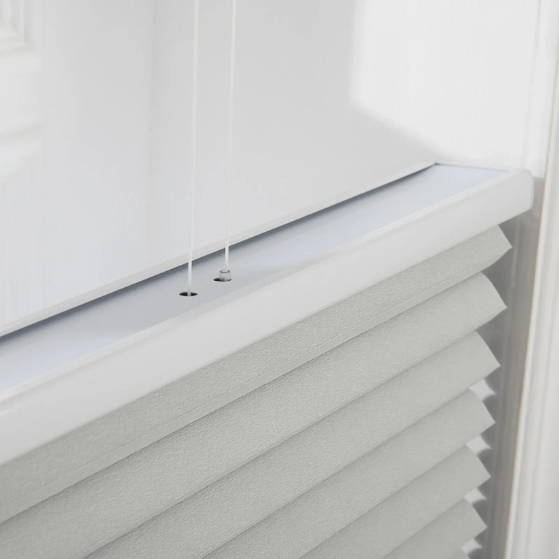 Photography of modern white pleated cellular Blinds on an interior window, featuring a crisp white top rail, two thin control cords, and textured gray-white fabric